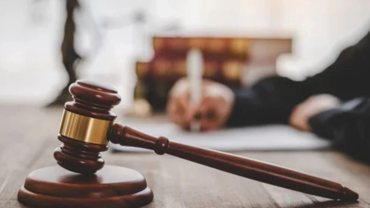 Ahşap mahkeme tokmağı ve arka planda evrak inceleyen kişi