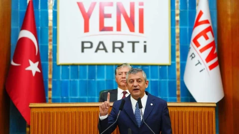 Yeni Parti tabelası ve parti bayrağı önünde konuşma yapan bir kişi