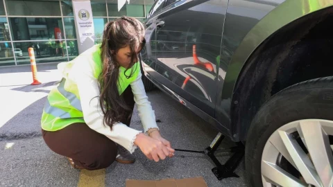 Kadın sürücü, araç lastiğini değiştirmek için krikoyla aracı kaldırıyor