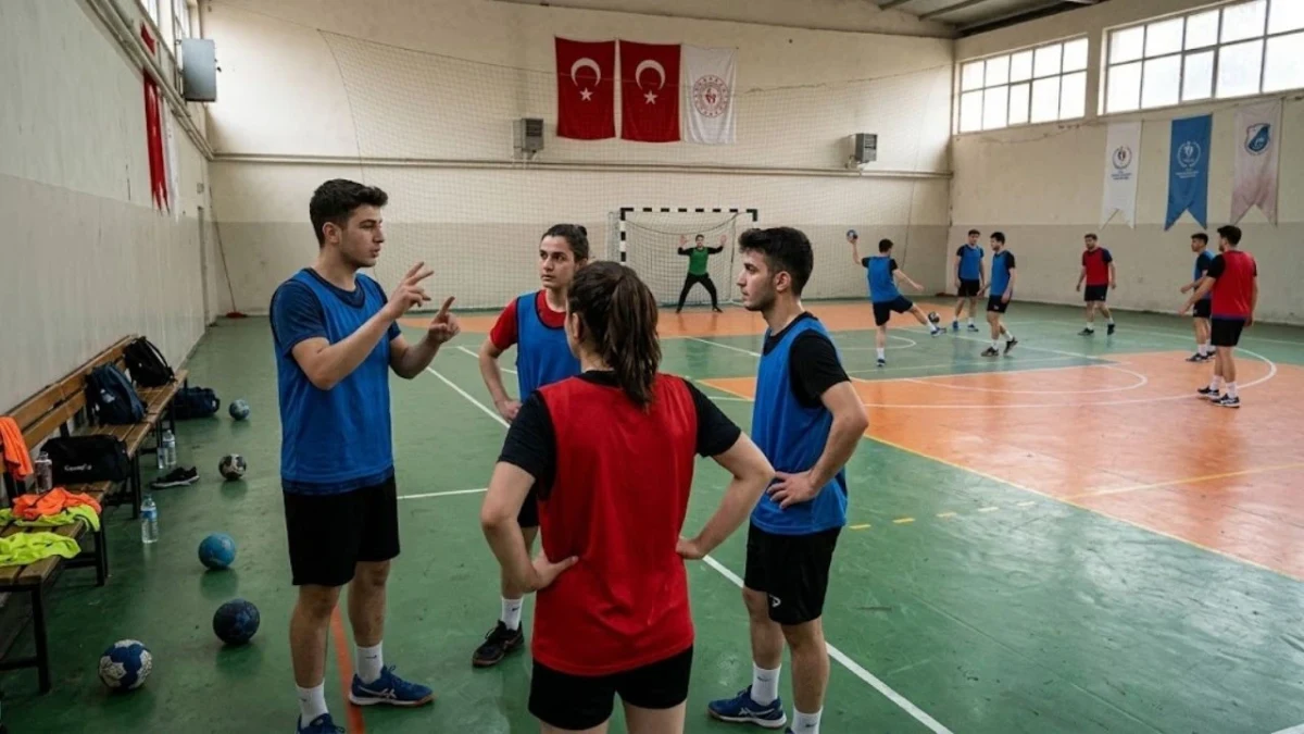 Hentbol salonunda antrenör sporcularla iletişim kuruyor, diğer sporcular sahada çalışıyor