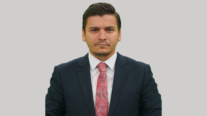 Yusuf Akın, koyu renk takım elbise ve desenli kravatla kameraya bakıyor