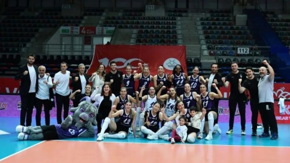 Voleybol takımı oyuncuları ve teknik ekibi saha içinde birlikte poz veriyor.